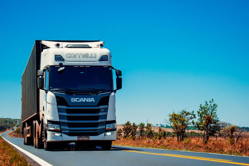 Caminhão de distribuição em rodovia sob céu aberto