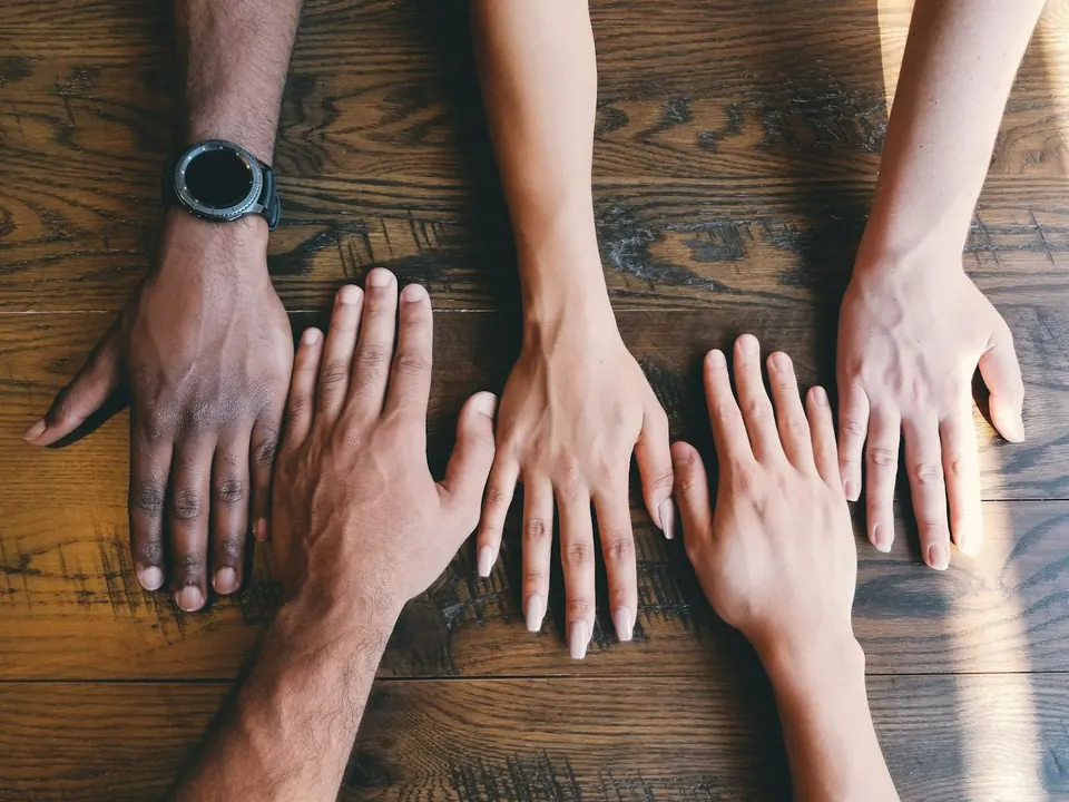 Mãos de diferentes pessoas reunidas sobre uma mesa